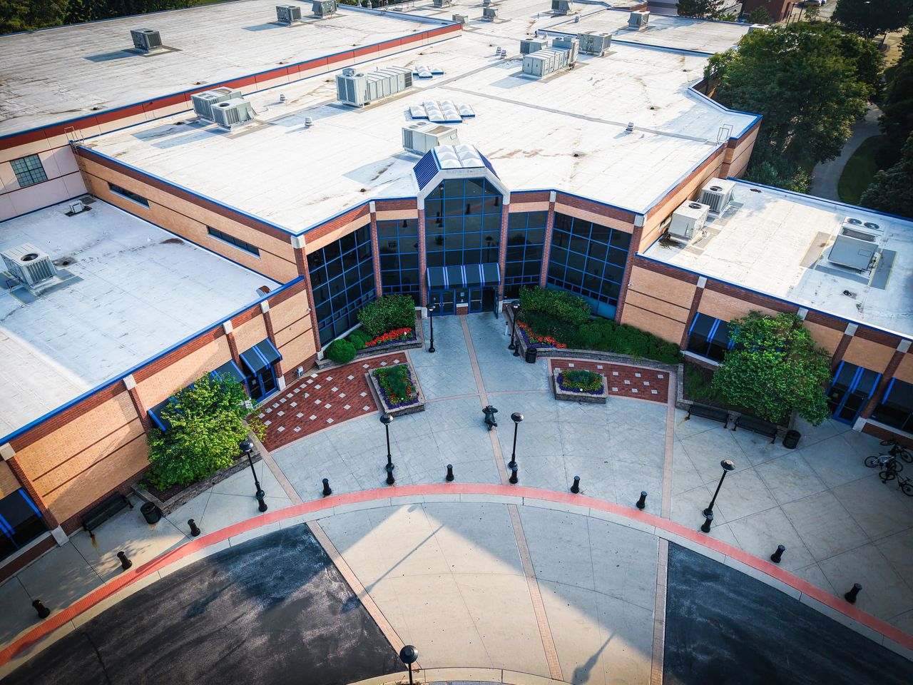 services-03 Aerial view of a modern building with glass windows and landscaped entrance.