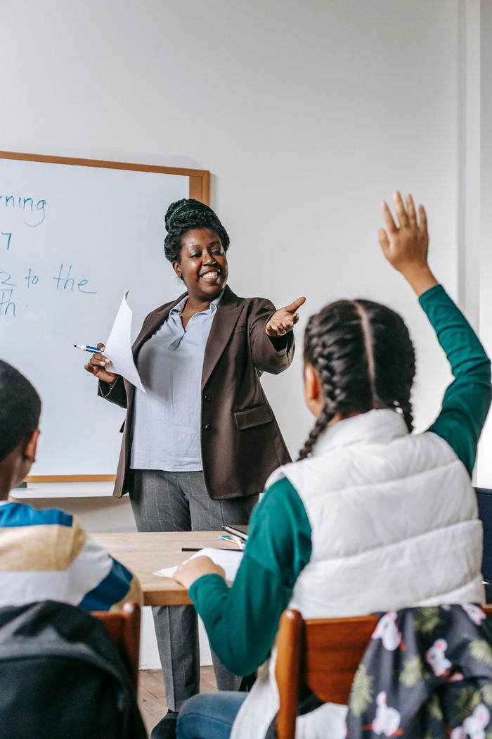 services-01 Smiling African American woman offering schoolgirl to ask question during lesson in school classroom