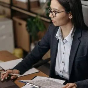 Asian woman in blazer working with documents at office desk. Ideal for business and work themes.