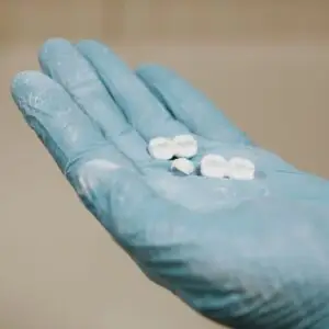 White artificial teeth for denture placed on hand in blue latex glove against light blurred background